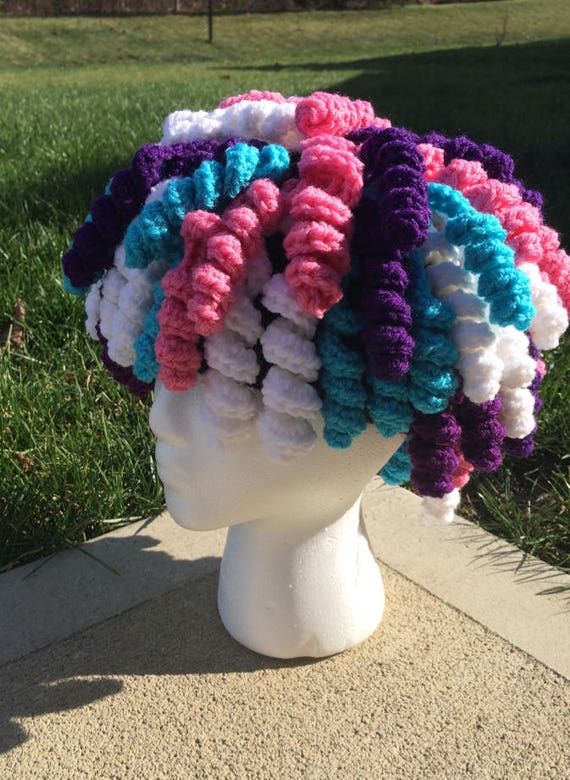 a white mannequin head with multicolored crocheted hair on it