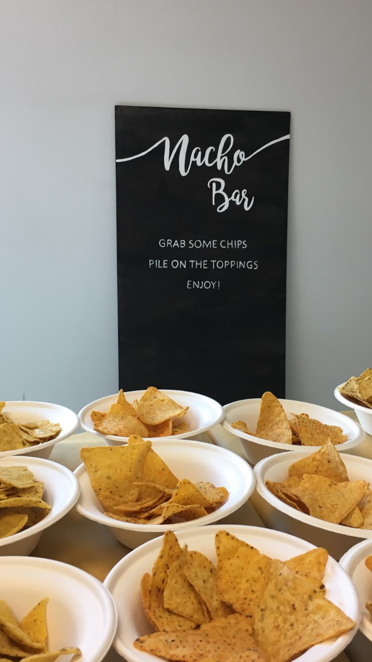 many white plates with chips on them and a black sign in the background that says nacho bar