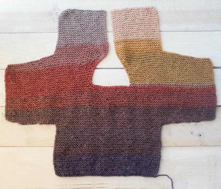 two knitted mitts sitting next to each other on top of a wooden floor