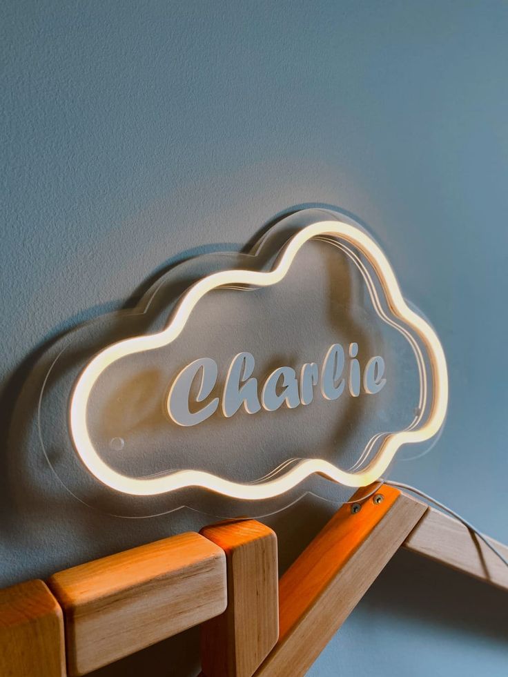 a neon sign that says charlie on it next to a wooden shelf with two chairs