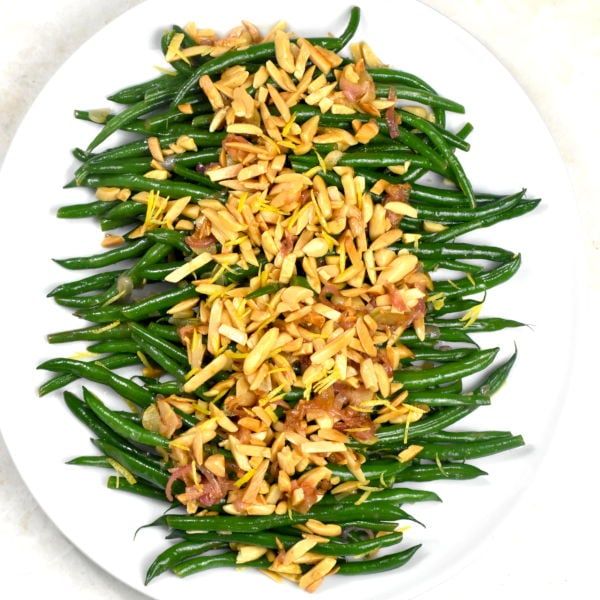 a white plate topped with green beans covered in yellow food colorings and seasoning