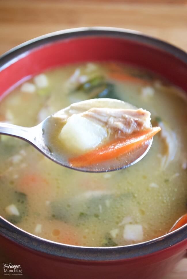 a spoon full of soup with broth and carrots