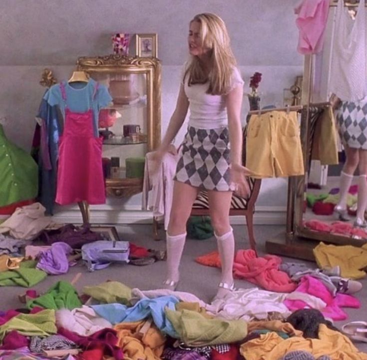 a woman standing on top of a pile of clothes in a room filled with clothing