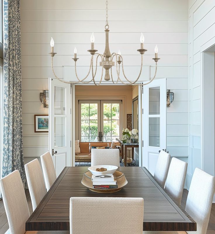 a dining room table with white chairs and a chandelier