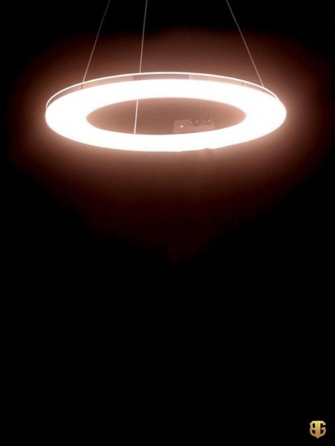 a circular light hanging from the ceiling in a dark room with black walls and flooring