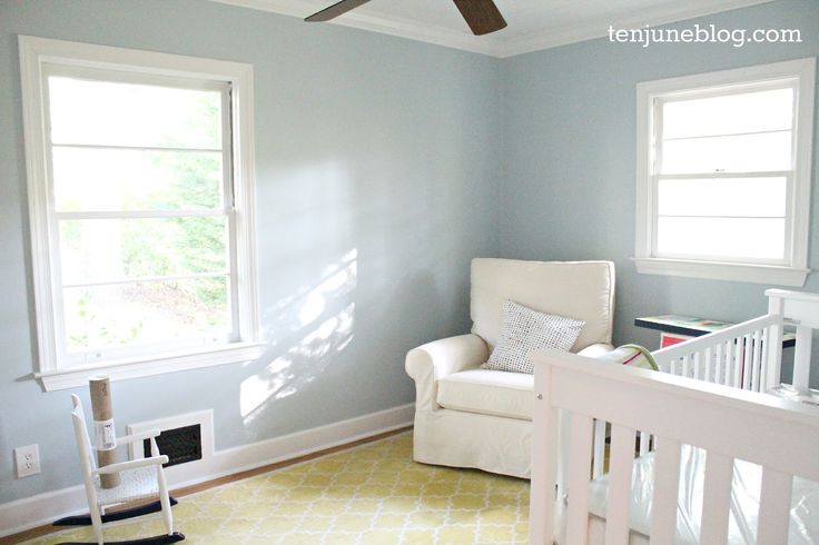 a baby's room with a crib, rocking chair and window in it