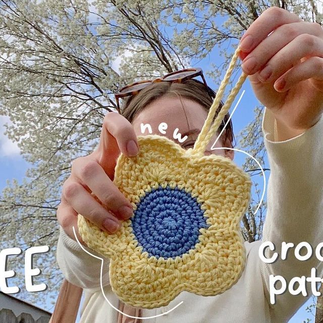 a woman holding up a crocheted flower pot holder in front of her face