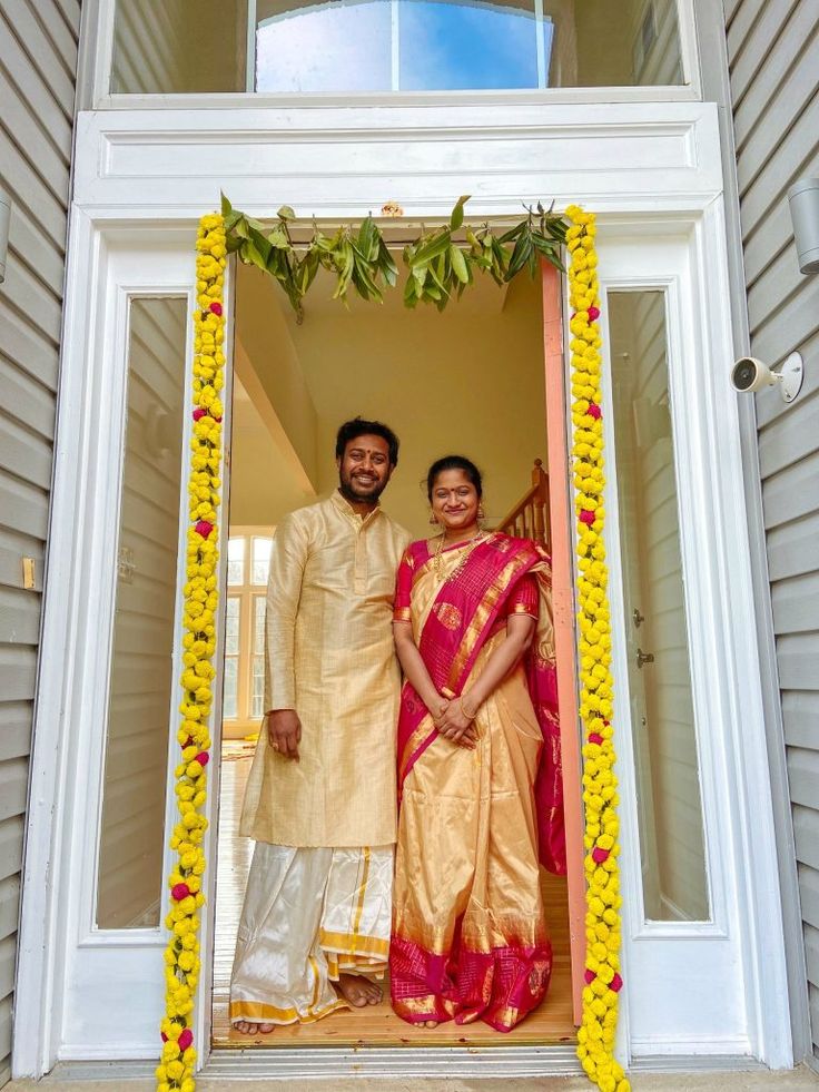 a man and woman standing in front of a doorway with flowers on the door frame