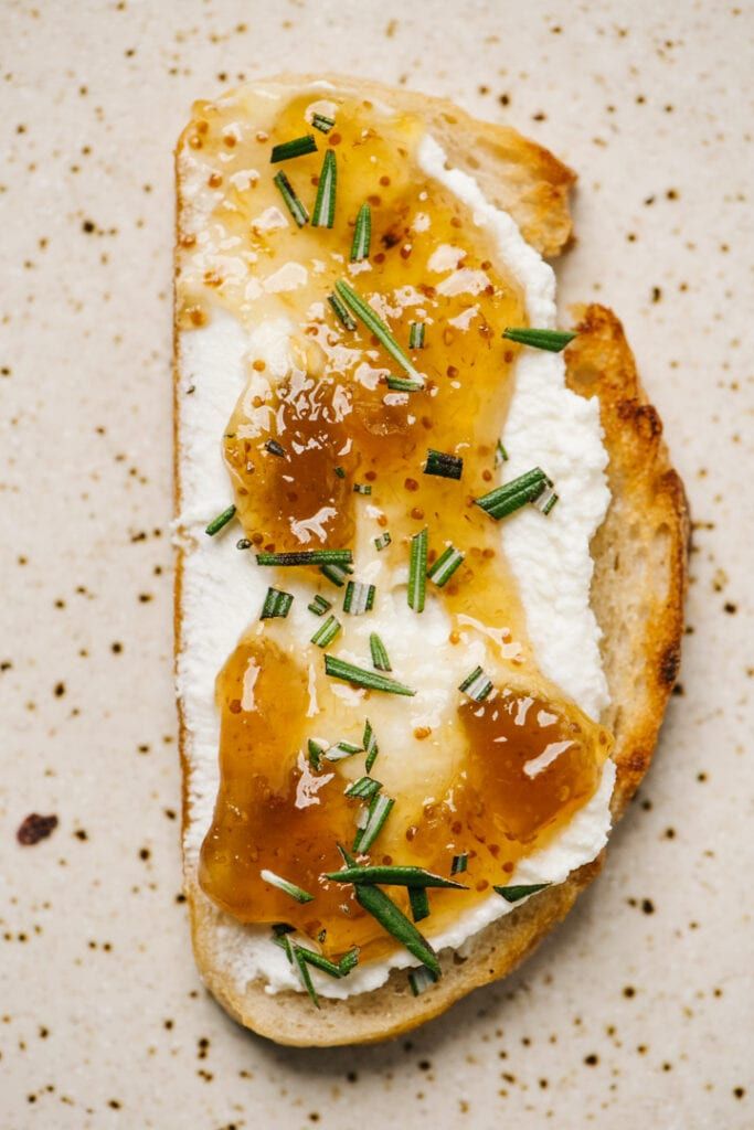 a piece of bread with cheese and herbs on it sitting on top of a table