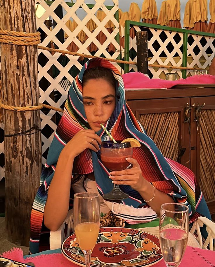 a woman sitting at a table holding a drink