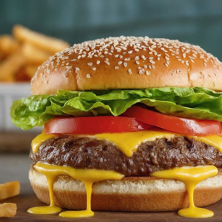 a cheeseburger with lettuce, tomato and onion on a wooden table