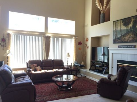 a living room with couches, chairs and a fire place in front of a window