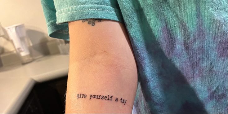 a person with a tattoo saying live yourself and try