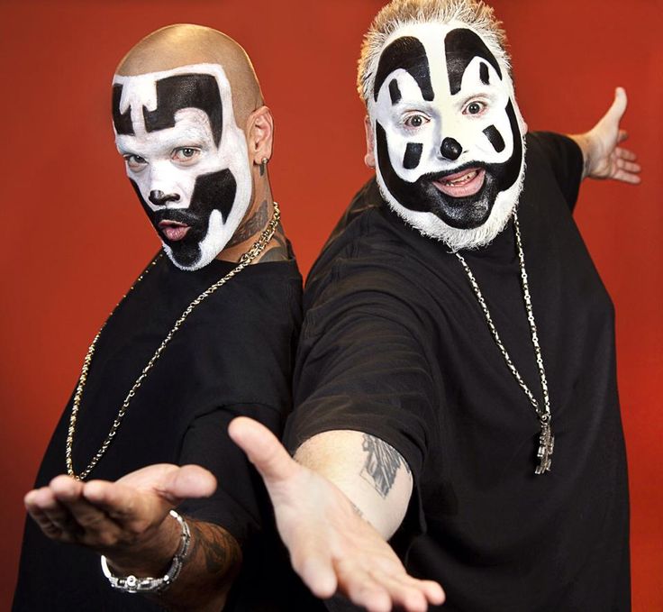 two men with painted faces and chains on their face are posing for the camera in front of a red background