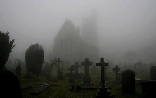 an old church in the fog with tombstones