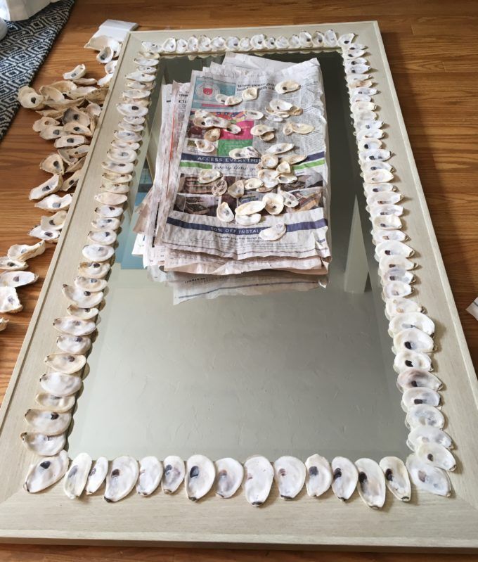 there is a mirror that has shells on it and some papers in front of it