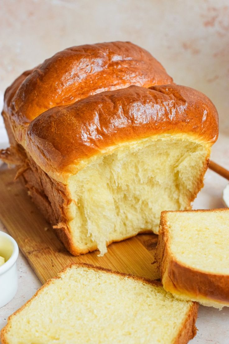 a loaf of bread sitting on top of a wooden cutting board next to some butter