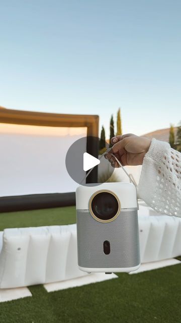 a person is holding an item in their hand while standing on artificial grass with a screen behind them