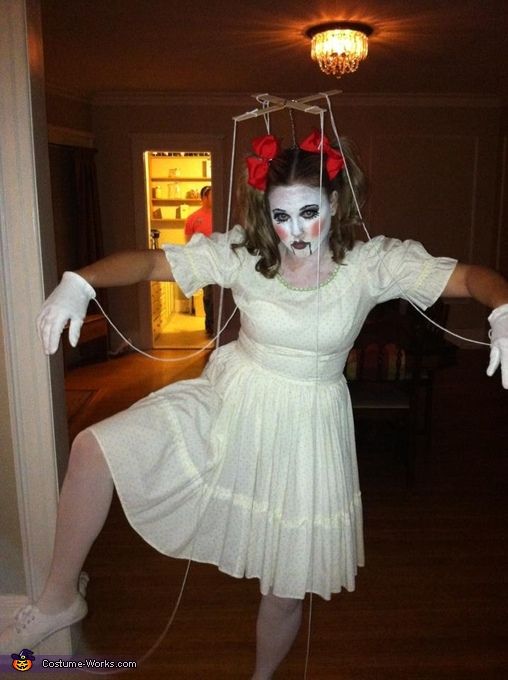 a woman in white dress and mask with hands on strings