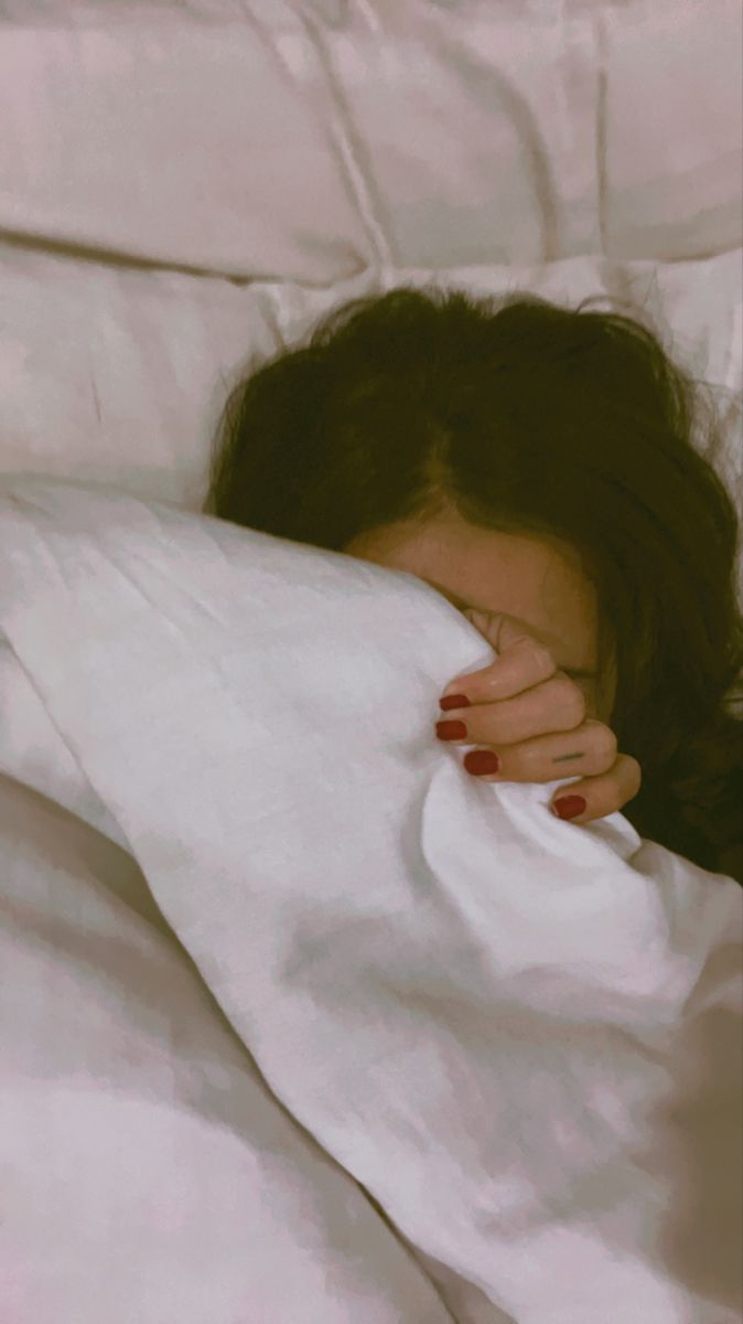 a woman laying in bed with her head on the pillow