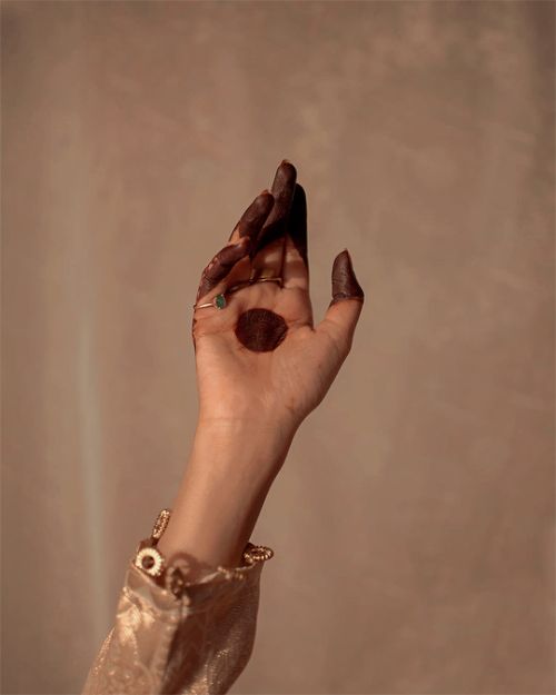 a woman's hand holding something in the air with her fingers and nails painted brown