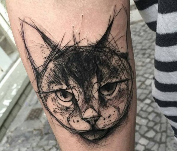 a black and white cat tattoo on the left leg, with an abstract design behind it