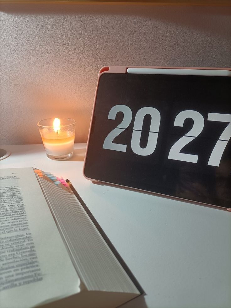 a table with a lit candle and a book on it