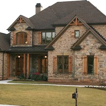 a large brick house with lots of windows on it's front porch and side yard