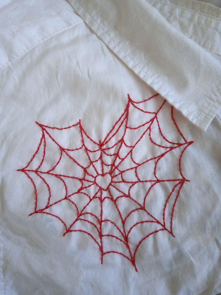 a spider web on a white shirt with red thread