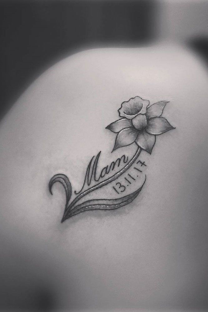 the back of a woman's shoulder with a flower and name tattoo on it