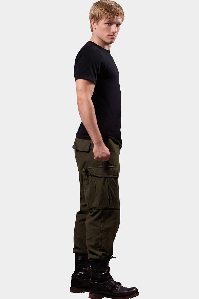 a man in black shirt and cargo pants standing with his hand on his hip pocket