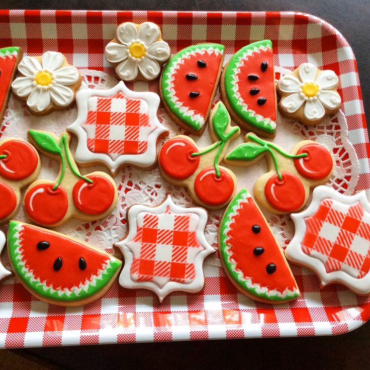 decorated cookies in the shape of watermelon on a red and white checkered tray