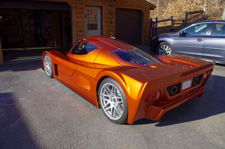 an orange sports car parked in front of a building