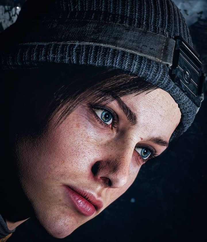 a woman with freckled hair wearing a beanie and looking at the camera