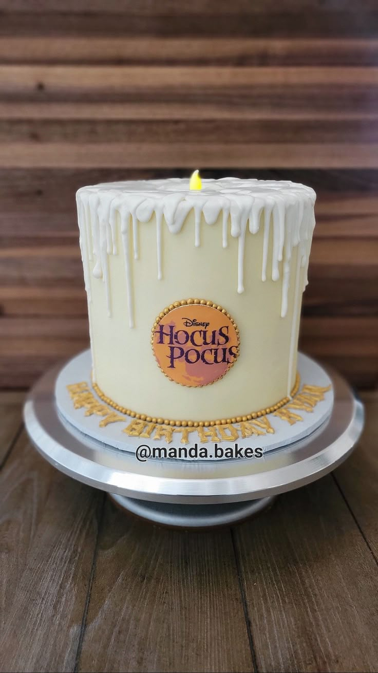 a white cake with icing and a yellow candle on top is sitting on a silver platter