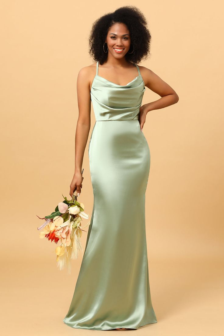 a woman in a long green dress holding a bouquet and posing for the camera with her hand on her hip