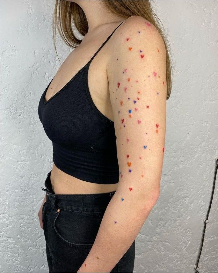 a woman with tattoos on her arm and chest is standing in front of a white wall