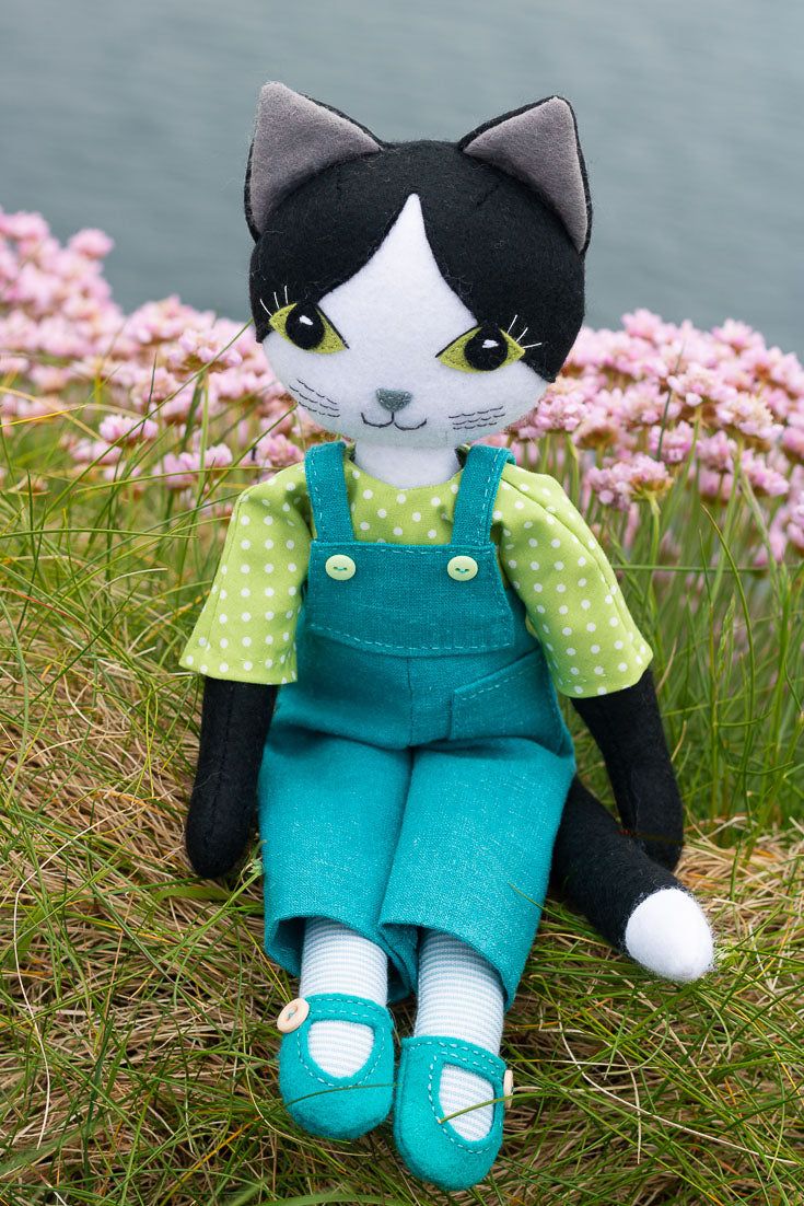 a black and white cat doll sitting in the grass