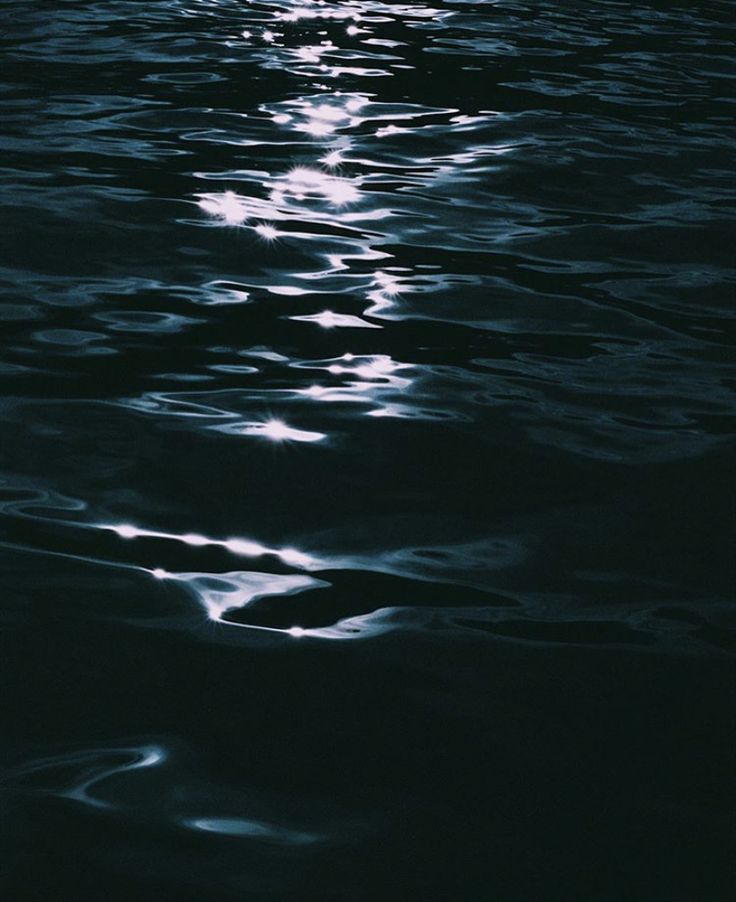 the moon is reflected in the water at night