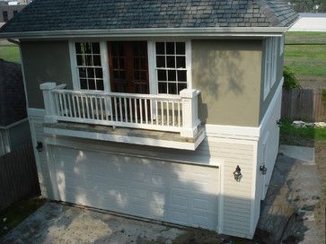 a small house with a white porch and two garage doors on the side of it