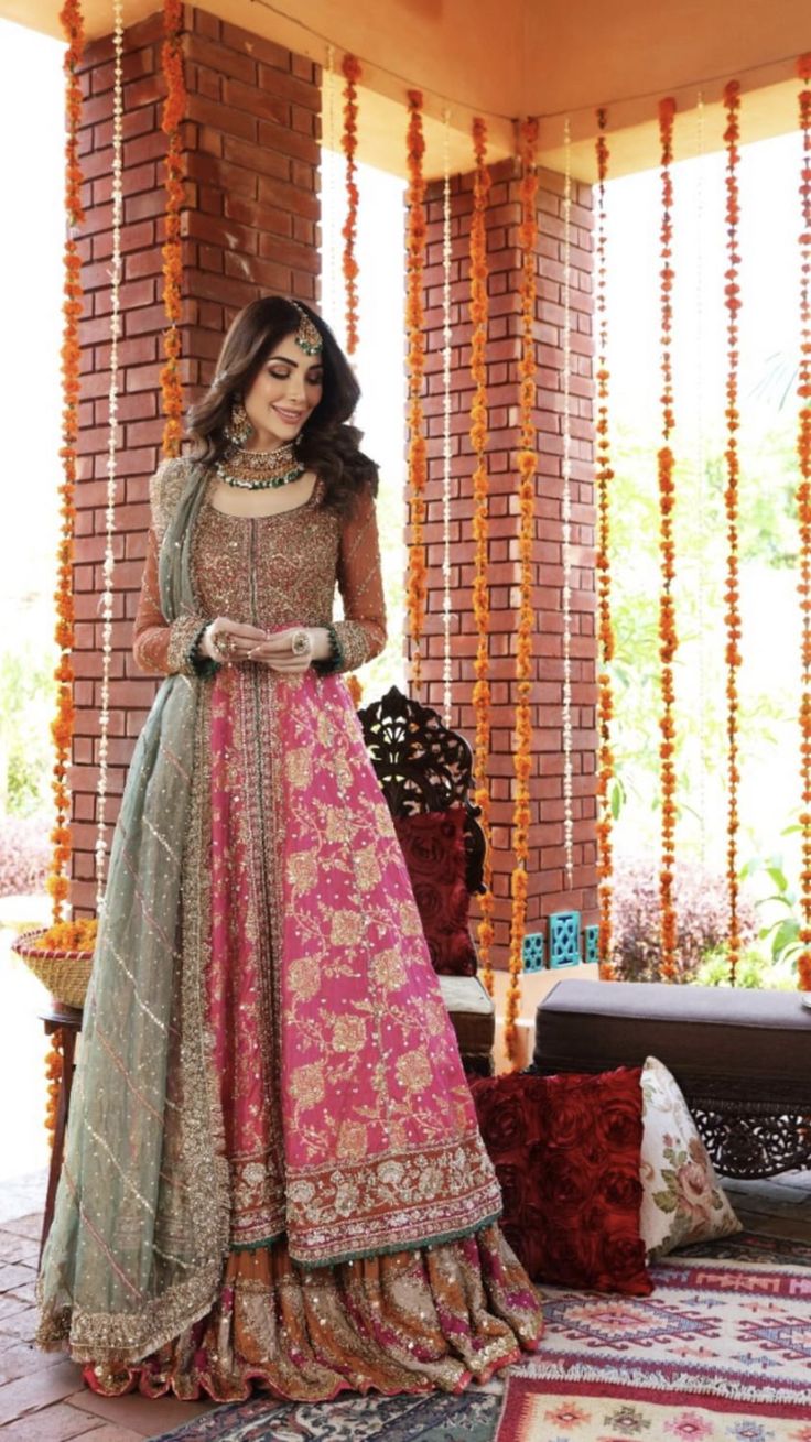 a woman in a pink and green lehenga standing on a rug with flowers