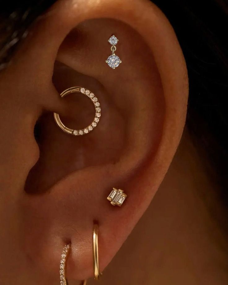 a woman's ear with three different types of piercings