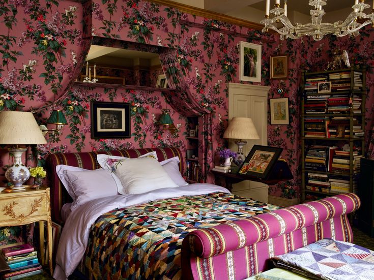 a bedroom with floral wallpaper and pink bedspread, chandelier, nightstands, and lamps