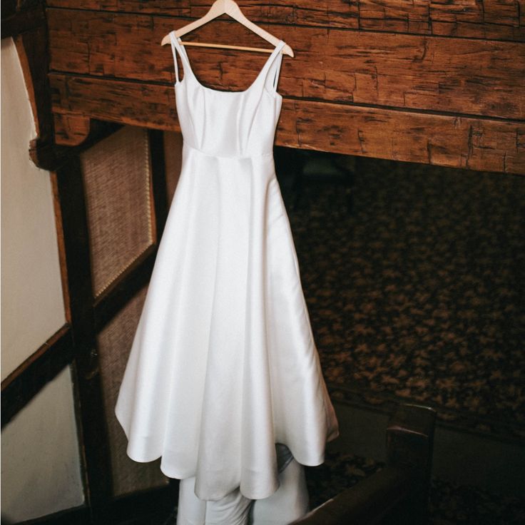 a white dress hanging on a wooden hanger