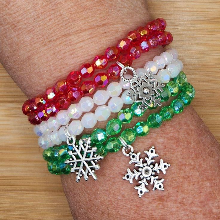 three bracelets with snowflakes and charms on the wrist, all in different colors