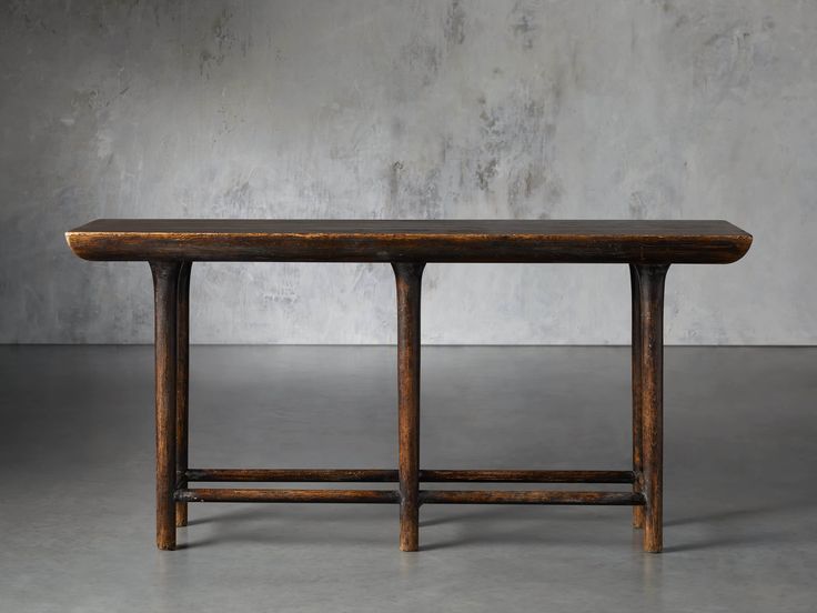 a wooden table sitting on top of a cement floor next to a concrete wall with no one around it