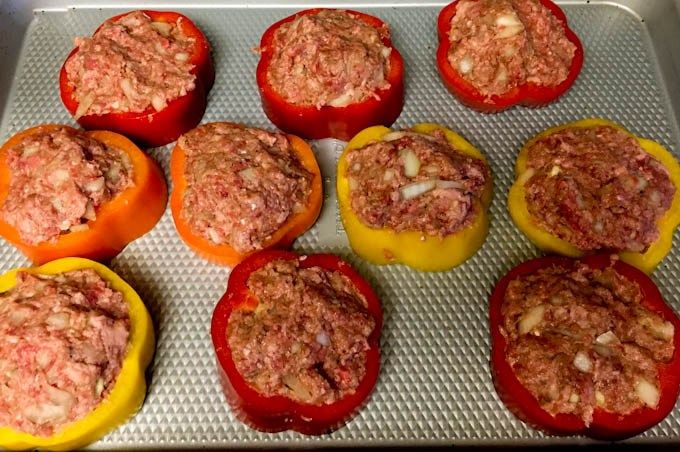 several stuffed peppers on a baking sheet ready to be cooked in the oven for dinner