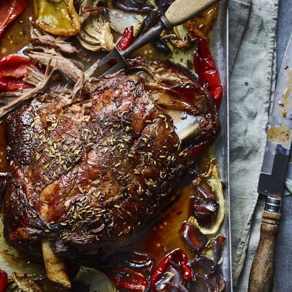 a large piece of meat sitting on top of a table next to vegetables and knives