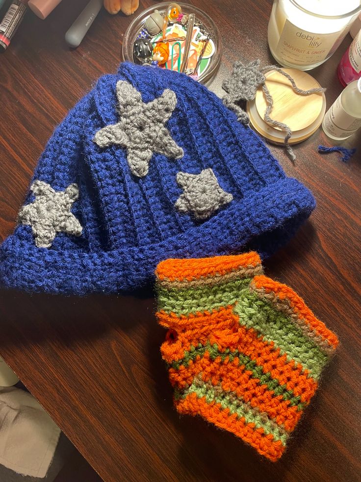 two crocheted hats sitting on top of a wooden table next to other items