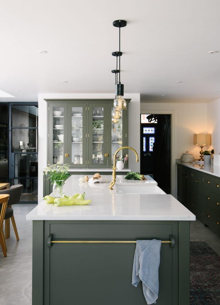 an instagram photo of a kitchen with green cabinets and white countertops in the middle